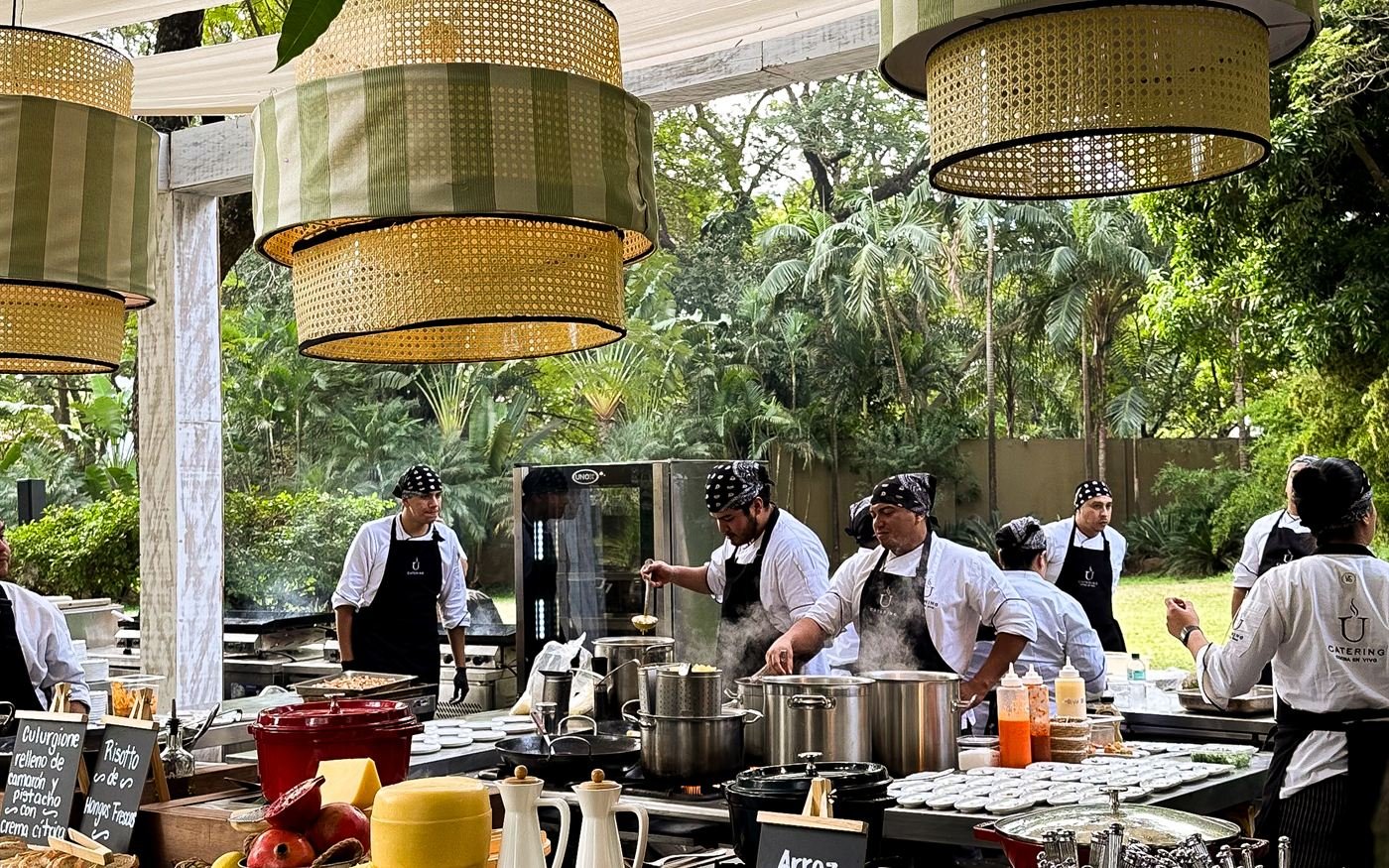 Estaciones de U Catering montadas bajo una pérgola durante un evento con invitados