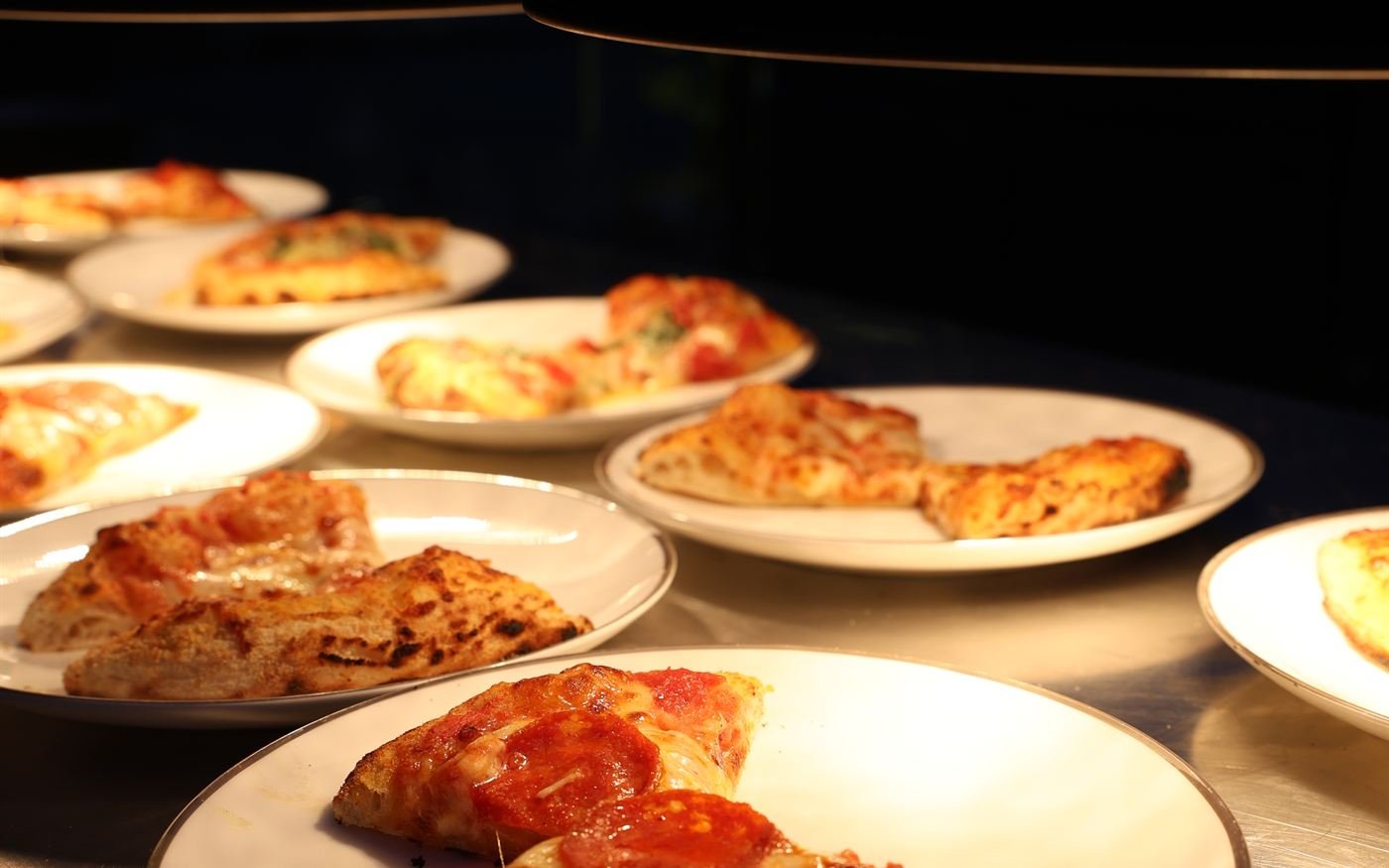 Pizzas recién horneadas servidas en platos con luz cálida de noche