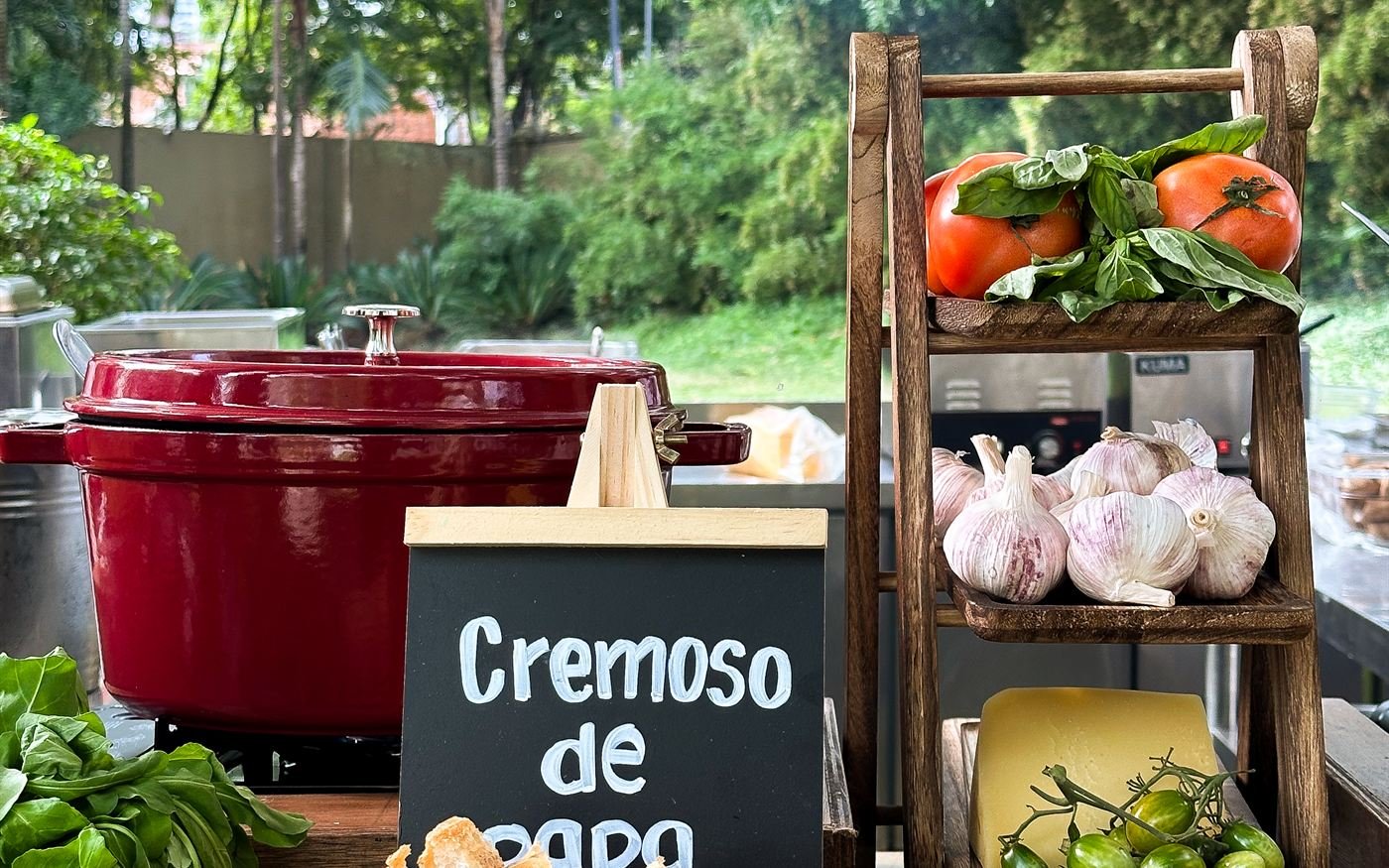 Estación de cremoso de papa con ollas de hierro y verduras frescas en un evento al aire libre
